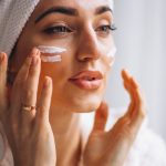 Femme qui se met de la crème sur le visage