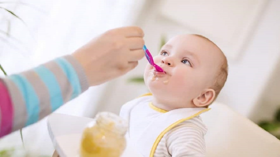 Bébé qui mange un pot de légumes bio